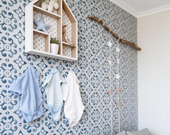 Puede incluir: Un estante de pared de madera con forma de casa en acabado blanco y madera natural, que contiene pequeños peluches y una suculenta. Tres bodies de bebé en azul sólido, rayas azules y blancas, y blanco sólido cuelgan en la pared.