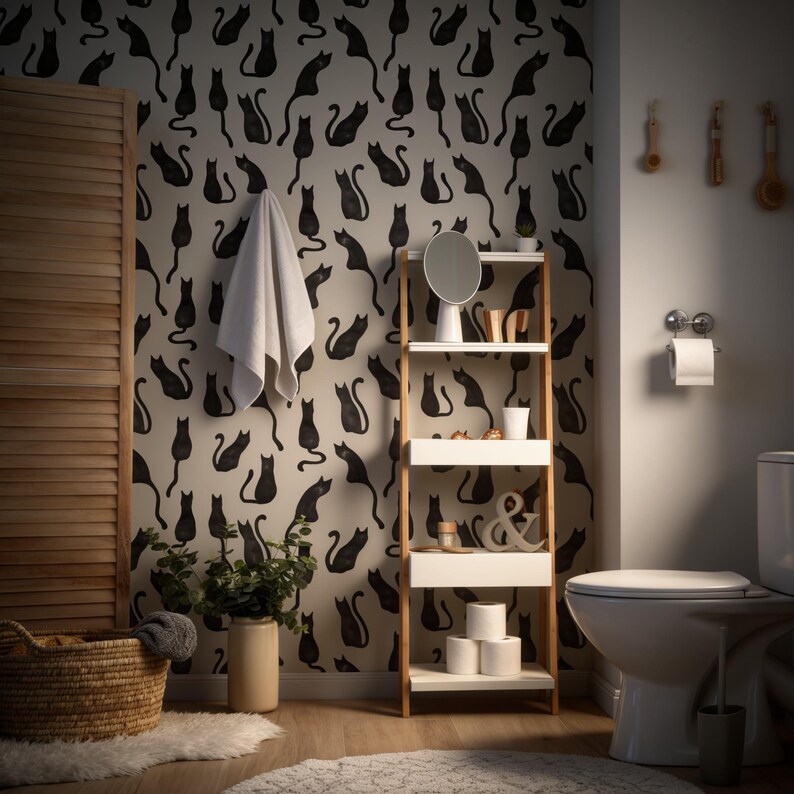 Puede incluir: Un ba&ntilde;o con papel tapiz de patr&oacute;n repetido de gatos negros. Una estanter&iacute;a alta de madera clara con estantes blancos sostiene un espejo redondo, una taza blanca y rollos de papel higi&eacute;nico. Una toalla blanca cuelga cerca y hay una cesta tejida.