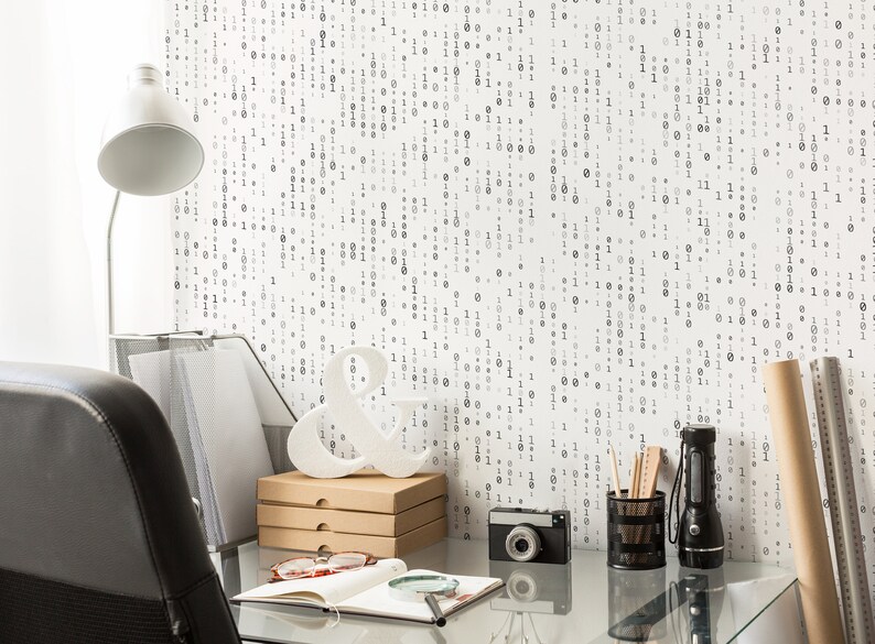 May include: A home office desk with a white lamp, a black leather chair, a white ampersand, a camera, a notebook, a magnifying glass, and a black pencil holder with pencils. The wall behind the desk is covered in a white wallpaper with a black binary code pattern.