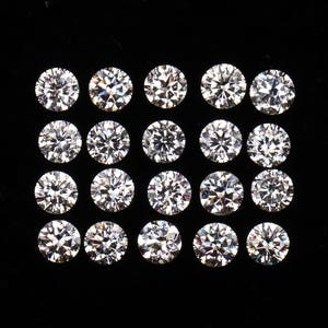 Puede incluir: Veinte diamantes de talla redonda se disponen en una cuadrícula sobre un fondo negro. Los diamantes, claros y brillantes, reflejan la luz. La imagen muestra el brillo y las facetas de las piedras preciosas, destacando su claridad y talla.