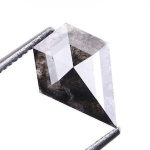 May include: A black diamond with a kite shape cut. The diamond is held by a pair of tweezers.