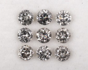 May include: Nine round, gray, faceted gemstones on a white surface. The gemstones are arranged in three rows of three.