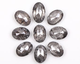 Pode incluir: Nove diamantes cinzentos ovais dispostos em um padrão circular. Cada diamante tem múltiplas facetas que refletem a luz, criando um efeito brilhante. Os diamantes estão sobre um fundo branco liso.