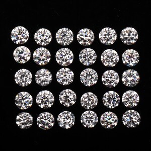 May include: A collection of round, brilliant-cut diamonds arranged in a grid pattern against a black background. The diamonds sparkle with multiple facets, reflecting light. The image showcases the clarity and brilliance of the gemstones.