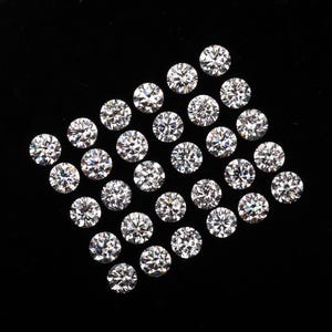 May include: A collection of round, brilliant-cut diamonds arranged on a black background. The diamonds are clear and sparkling, reflecting light. The arrangement is a diamond shape, showcasing the gems' facets.