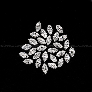 May include: A cluster of marquise-cut diamonds displayed on a black background. The diamonds are clear and reflect light. The arrangement is circular, with the diamonds fanning out from a central point.