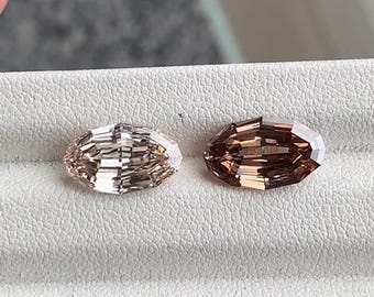May include: Two faceted oval gemstones. One is a light champagne color, and the other is a darker, reddish-brown hue. The gems are displayed on a white surface, showcasing their cut and clarity. Ideal for jewelry making.