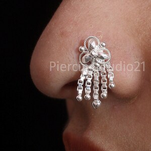 May include: Silver nose ring with a floral design and a dangling chain of small beads.