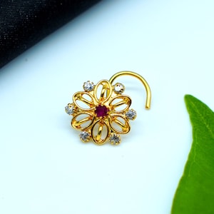 May include: Gold nose ring with a flower design featuring white stones and a single red stone in the center.