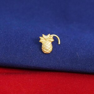 May include: Gold pineapple nose ring with a curved post. The nose ring is a popular piece of jewelry for women.