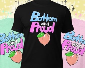 May include: Three t-shirts in mint green, black, and pink, each featuring the text "Bottom and Proud" in blue and pink, with a peach graphic. The shirts are casual wear.