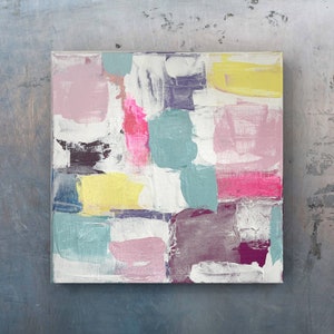May include: Abstract painting with a colorful geometric design. The painting features shades of pink, yellow, teal, purple, and white.