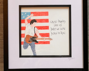 May include: A framed drawing of a person playing a guitar in front of an American flag. The drawing is in black and white with red, white, and blue accents. The text "Cause Tramps Like Us Baby We Were Born To Run" is written in black ink on the right side of the drawing. The drawing is signed "Moonlace" in the bottom right corner.