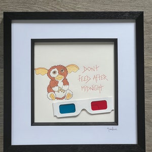 Gizmo van Gremlins, met de hand getekend met &#39;Niet eten na middernacht&#39; met de hand geschreven ernaast en een retro 3D-bril bevestigd.