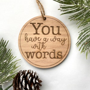 May include: A wooden Christmas ornament with the text "You have a way with words" engraved on it.