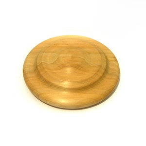 May include: A round, light-colored wooden coaster with a raised edge and a central recessed area. The coaster is made of natural wood and has a smooth, polished finish. The diameter is approximately 5 inches.