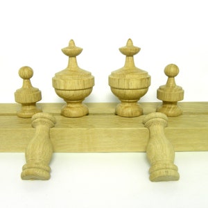 May include: Five wooden finials in various sizes and styles, including a ball finial, a finial with a pointed top, and a finial with a rounded top. The finials are arranged on a wooden base.