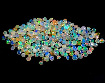 Puede incluir: Una colección de ópalos pequeños y redondos con una variedad de colores, incluyendo blanco, azul, verde y naranja. Los ópalos están dispersos sobre un fondo negro, creando una exhibición visualmente atractiva de piedras preciosas. Los ópalos son de varios tamaños.