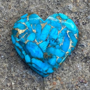 May include: A heart-shaped turquoise stone with gold veins. The stone is a deep blue colour and has a smooth, polished surface.