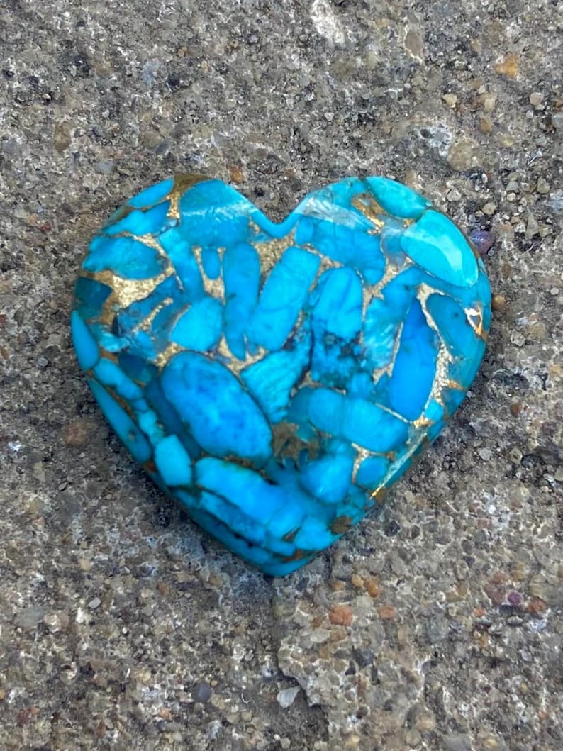 May include: A heart-shaped turquoise stone with gold veins. The stone is a deep blue colour and has a smooth, polished surface.