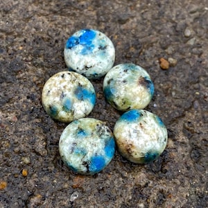 May include: Five round, polished stones with a white, blue, and black marbled pattern.