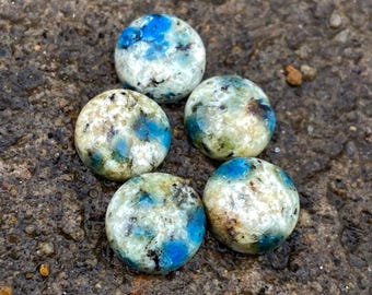 May include: Five round, polished stones with a white, blue, and black marbled pattern.