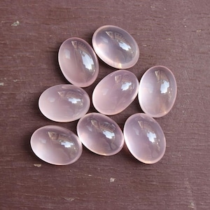 Pode incluir: Oito pedras de quartzo rosa de forma oval, cada uma com uma superfície lisa e polida e um tom rosa translúcido.