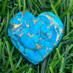 May include: A heart-shaped turquoise stone with gold veins. The stone is a deep blue colour and has a smooth, polished finish.