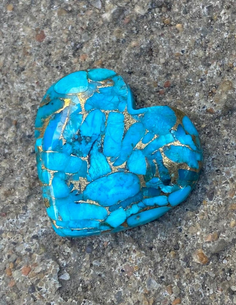 May include: A heart-shaped turquoise stone with gold flecks. The stone is a deep blue colour and has a smooth, polished surface.