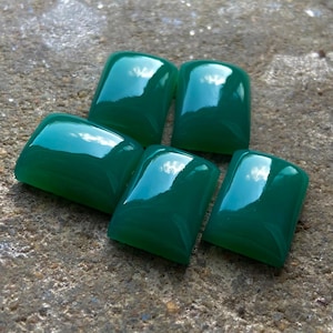 May include: Five smooth, polished, green gemstone cabochons. The cabochons are rectangular in shape and have a glossy finish.