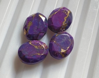 Può includere: Quattro cabochon ovali in pietra preziosa viola e dorata. Le pietre hanno un taglio sfaccettato e sono disposte in un gruppo.