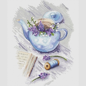 May include: A cross-stitch design featuring a light blue teapot with white polka dots, filled with purple flowers and white lily of the valley. A spool of blue thread and a notebook are also present, creating a serene, floral theme.