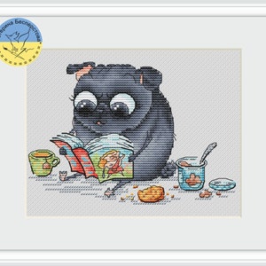 May include: A black pug dog with big eyes is sitting and reading a colorful book. The dog is surrounded by a cup of tea, a jar of jam, and scattered cookies.