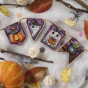 May include: A Halloween-themed banner with five flags. Each flag features a different embroidered design: a black cat with a pumpkin, a ghost with a pumpkin, a ghost with a pumpkin, a witch with a hat, and a cauldron with a green potion.