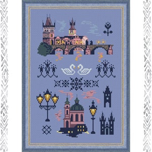 May include: A cross-stitch pattern featuring a blue cityscape with a bridge, swans, and streetlights. The pattern includes a church with a pink dome and a castle with a tall tower. The pattern is framed in a blue frame.