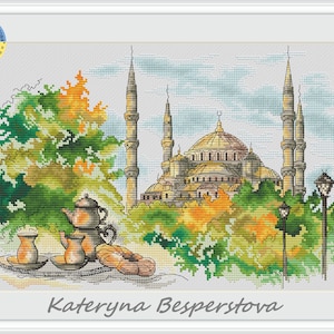 May include: Cross-stitch artwork depicting a mosque with multiple minarets and a large dome, surrounded by green and orange foliage. A tea set and pastry are in the foreground. The artist's name, Kateryna Besperstova, is at the bottom.
