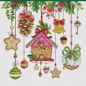 Op de afbeelding: Een witte achtergrond met een verscheidenheid aan kerstversieringen die aan een groene krans hangen. De versieringen omvatten een peperkoekster, een vogelhuisje, een dennenappel, een bel, een sleutel, een eikel en een peperkoekbal.