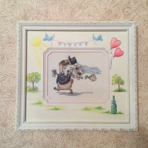 Peut inclure: Une broderie au point de croix encadr&eacute;e repr&eacute;sentant une sc&egrave;ne de mariage de dessin anim&eacute; avec deux animaux, un lapin et un renard, v&ecirc;tus d'une tenue de mariage. La broderie est entour&eacute;e d'un cadre blanc avec une bordure d&eacute;corative. L'arri&egrave;re-plan comprend un soleil, des oiseaux bleus et une bouteille de champagne.
