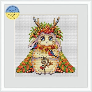 May include: A cross-stitch pattern featuring a white rabbit with large eyes, wearing a crown of autumn leaves and berries. Two small birds are perched on its arms. The background is a light gray.