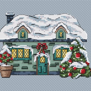 May include: A green brick house with a snowy roof and a green door. There are two small trees with red ornaments and snow on the branches in front of the house.