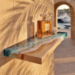 May include: A rectangular wooden wall shelf featuring a live edge and a glossy resin inlay that mimics ocean waves with shades of turquoise, blue, and white foam. A square glass perfume bottle with a gold cap and a white coral piece sit on top.