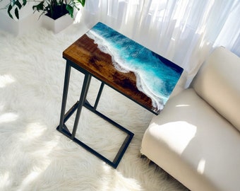 May include: A black metal side table with a wooden top featuring a blue and white resin ocean wave design.