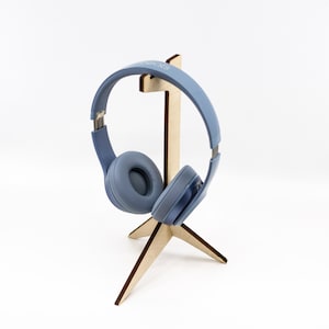 Könnte beinhalten: Ein hellblauer Kopfhörer auf einem Holzständer mit drei Beinen.