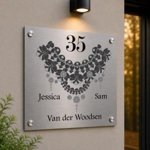 May include: A rectangular brushed metal house sign displaying the number 35 in black. The sign features a decorative floral design, the names "Jessica" and "Sam", and the surname "Van der Woodsen".