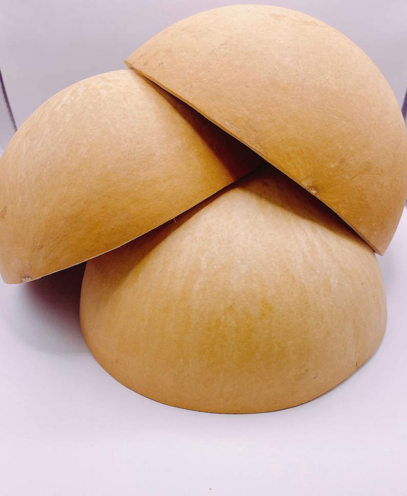May include: Three natural brown gourd bowls stacked on top of each other. The bowls are smooth and have a slightly textured surface.
