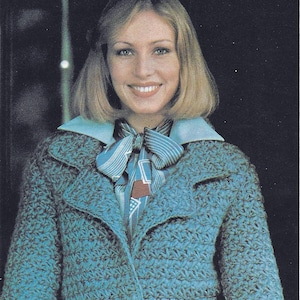 May include: A teal blue crocheted jacket with a large collar and pockets. The jacket has a tie at the waist and is made with a textured stitch.