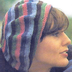 May include: A striped crocheted hat in shades of pink, green, blue and brown. The hat is being worn by a person with brown hair.
