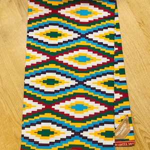 May include: A colorful fabric with a geometric pattern in shades of red, yellow, green, blue, and white. The fabric has a label that says "Hollantex 1844558".