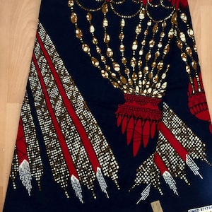May include: A blue and red fabric with a gold and white pattern. The pattern features a chandelier-like design with a red base and gold chains. The fabric has a white border.