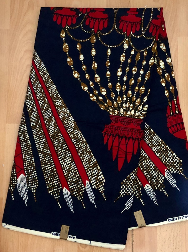 May include: A blue and red fabric with a gold and white pattern. The pattern features a chandelier-like design with a red base and gold chains. The fabric has a white border.